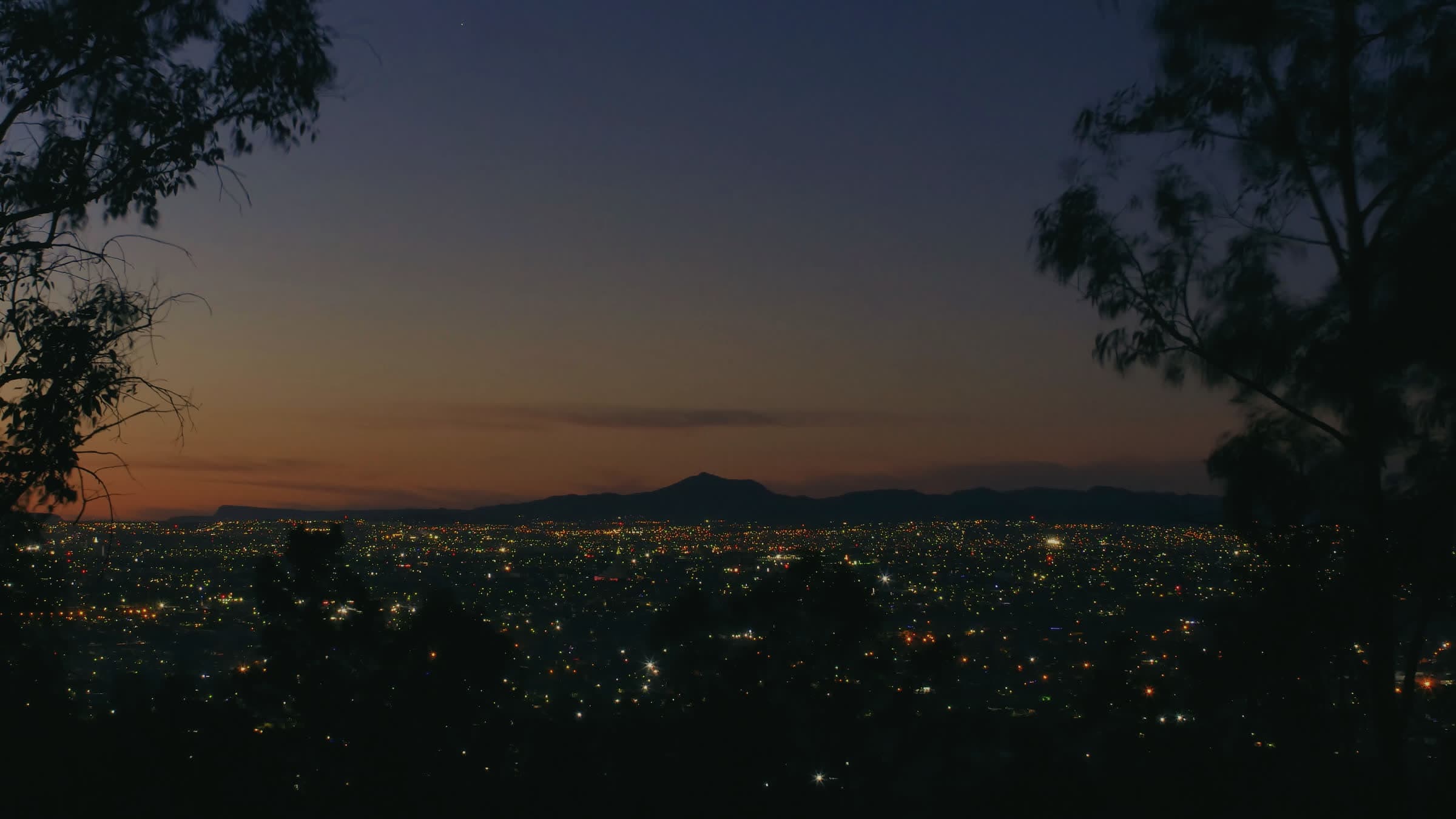 Dusk over a small town in a valley, house lights coming on