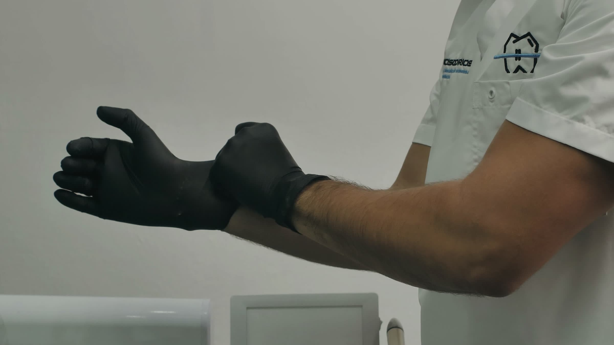 A dentist pulling on black gloves before an appointment