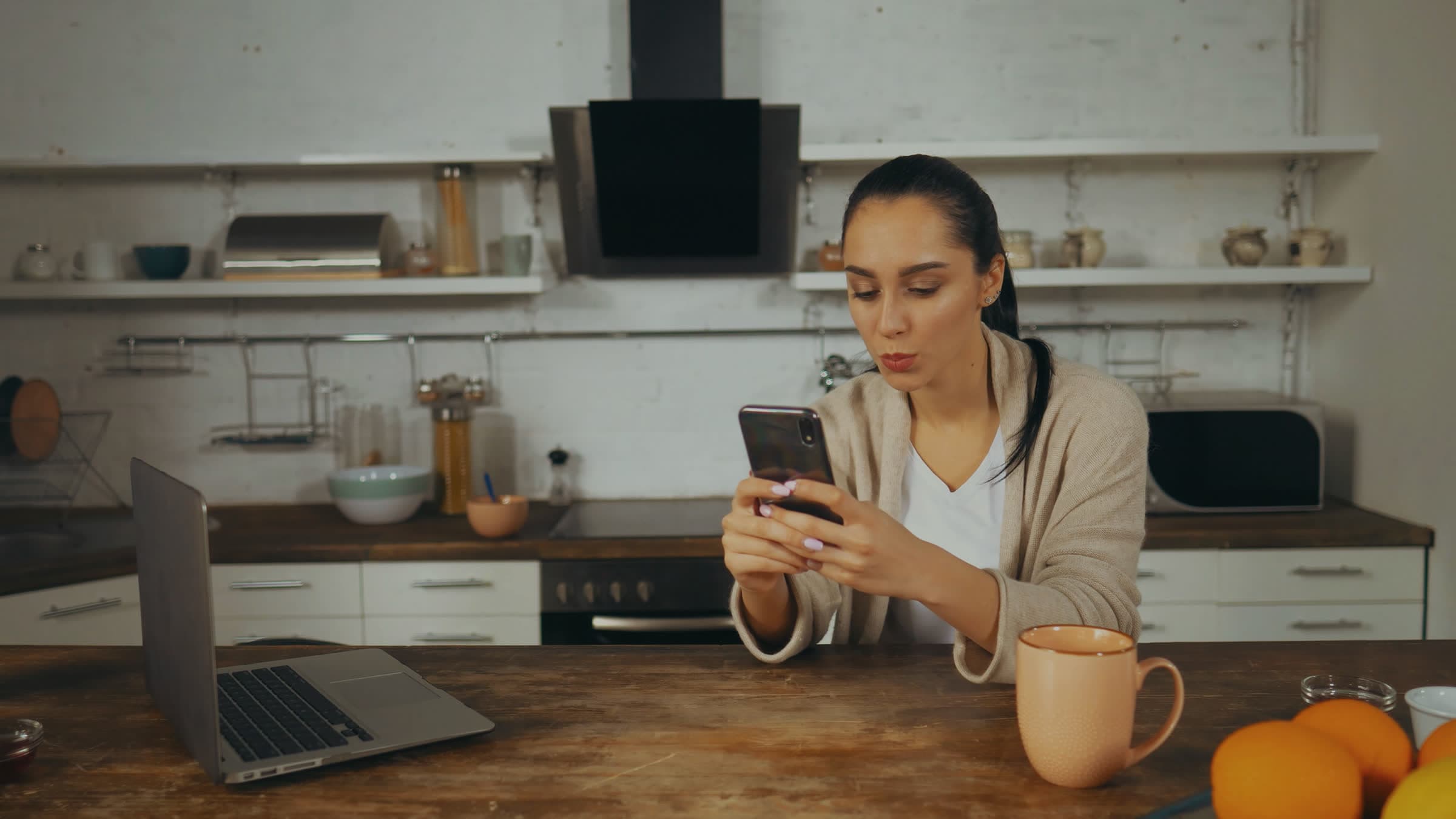A woman reading something on her phone at her kitchen table