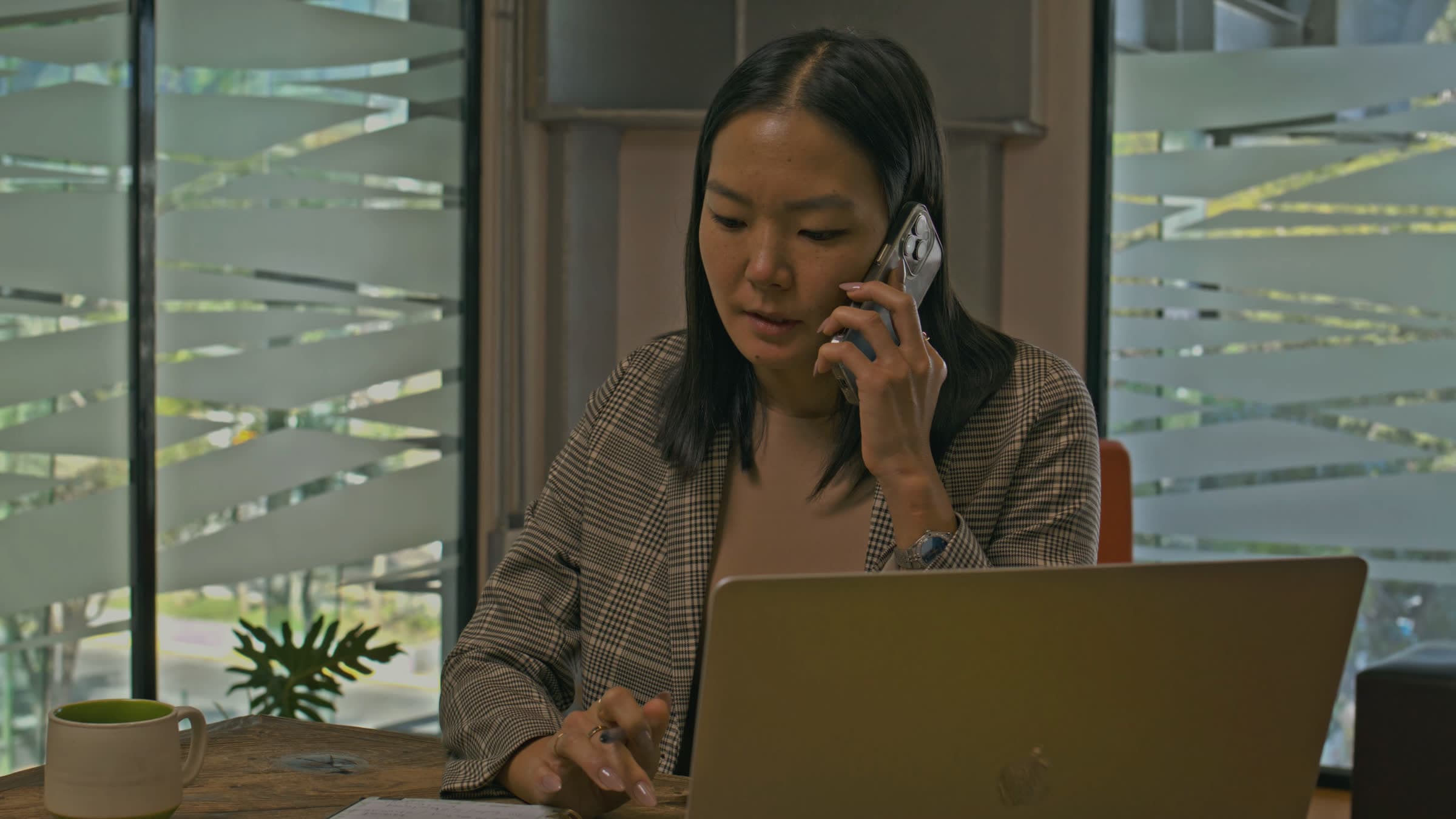 A practice manager on the phone, going through numbers on her laptop
