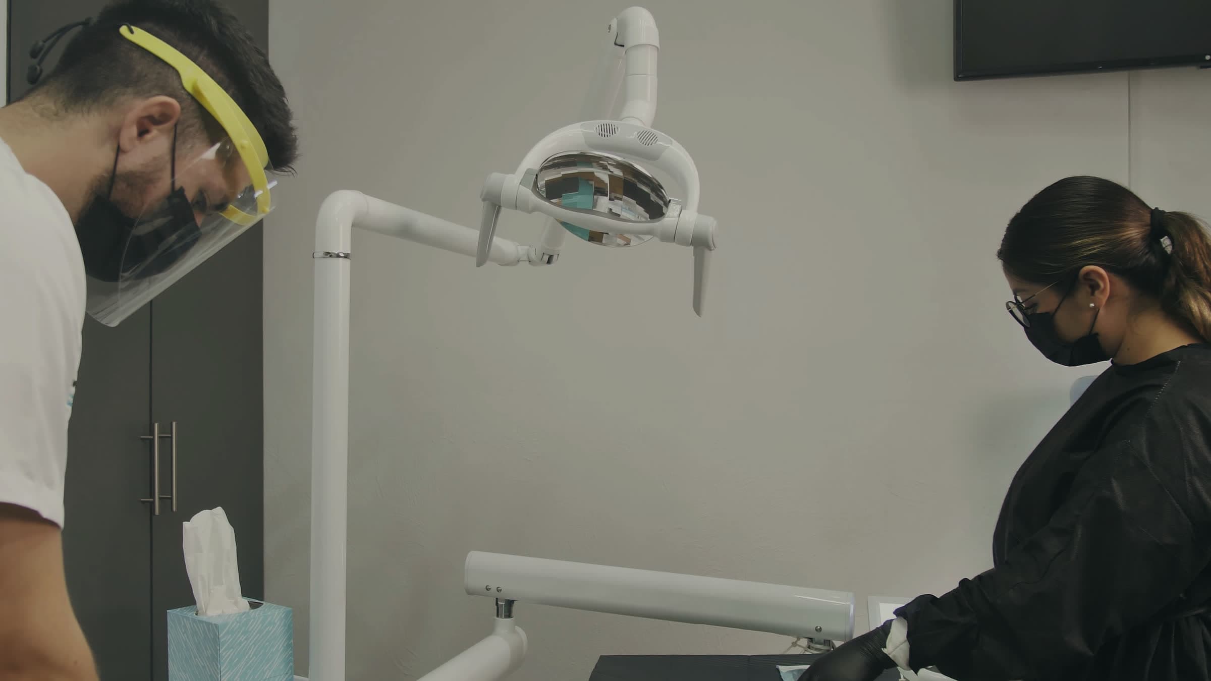 A bright dental operatory with the assistant preparing instruments
