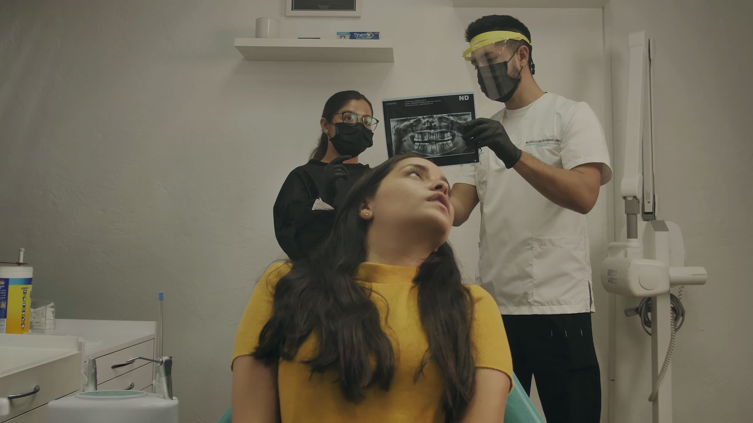 A dentist holding an X-ray up to the light while the patient looks on